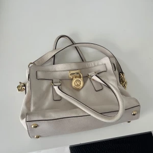 Damväska - Säljer en av mammas favoritväskor då den inte är till användning längre. Den är riktigt fin med en beige färg och guldiga detaljer. Väskan är i bra skick och redo för användning. Säljs billigt så först till kvarn!