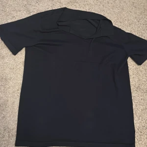 Mörkblå pikétröja från Lindex - Snygg mörkblå pikétröja från Lindex i storlek 170. Klassisk krage och korta ärmar, perfekt för en clean och stilren look. Tröjan är gjord i mjukt material som känns skönt mot huden och passar till många olika outfits.