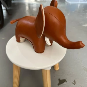 Züny elefant bokstöd i brunt skinn - Supersöt elefantformad bokstöd från Züny i brunt och beige konstläder. Perfekt som inredningsdetalj eller för att hålla ordning på böckerna i hyllan. Den har mjuka former och fina detaljer som stora öron och liten svans.