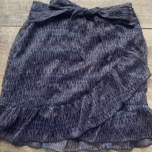 Kort kjol i glittrigt mönster - Mörk kort kjol från Neo Noir i ett mönster med tunna glittertrådar i. Superfin till fest och vardag! 