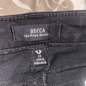 Svarta mid waist byxor från true religon - Säljer ett par svarta bootcut jeans från true religon i modellen Mid Rise Booter, storlek 24. Jeansen har medelhög midja och klassisk femficksdesign. Perfekta för dig som gillar en tidlös och snygg look.