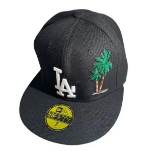 LA Cap Svart -  Modell: LA-keps med unik palmdesign framtill – en snygg twist på en klassiker  🎨 Färg: Stilren svart med detaljrik palmtryck och LA-logga på framsidan (se bilder för bästa färgåtergivning)  📏 Storlek: 56 cm – passar mindre till normal huvudstorlek (kolla gärna ditt mått vid osäkerhet)  🆕 Skick: Helt ny – aldrig använd och i perfekt skick  🧵 Material: Skön och lätt bomullsblandning – perfekt för både vardag och soliga dagar  🛒 Köp nu är tillgängligt!  Tack!