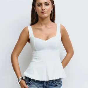 Vit pemplum top - Snygg vit korsett-topp med breda axelband och markerad midja. Toppen har en figurnära passform upptill och lätt utsvängd nertill, vilket ger en feminin siluett. Perfekt att styla med jeans eller kjol för en trendig look.
