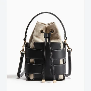 Beige och svart bucket bag med snörning - Snygg bucket bag i beige canvas och svarta skinn-detaljer. Väskan har justerbar axelrem, handtag och cool snörning upptill med guldfärgade metalldetaljer. Perfekt för dig som vill ha en trendig och praktisk väska med stilrena kontraster. Är inte helt säker på om jag vill sälja men skicka prisförslag💓