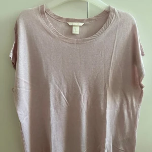 Ljusrosa oversized topp - Superfin ljusrosa oversized topp. Modellen är ärmlös med rund halsringning och har en mjuk, tunn stickad känsla. Perfekt för lager-på-lager eller som den är till jeans eller kjol