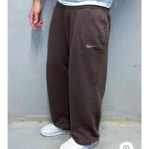 Nike wide sweatpants i olika färger - Säljer flera par Nike mjukisbyxor i loose fit och wide modell. Finns i brunt, grått, vitt och svart. Byxorna har resår i midjan, sidofickor och diskret Nike-logga på låret. Perfekta för chill eller streetwear. Tillverkade i mjuk bomullsmix har alla storlekar.