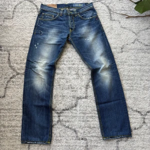 Blå dondup jeans  - Snygga blå jeans från Dondup med coola slitningar och ljusa partier framtill och baktill. Jeansen har raka ben, klassiska fem fickor och kontrastsömmar i gult och orange. Perfekta för en avslappnad streetstil. Hör gärna av er vid frågor! Obs pris ej hugget i sten