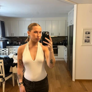 Vit halterneck body från ASOS  - Säljer en vit halterneck linnebody  med djup v-ringning och öppen rygg.  Från ASOS i storlek 38 (S)