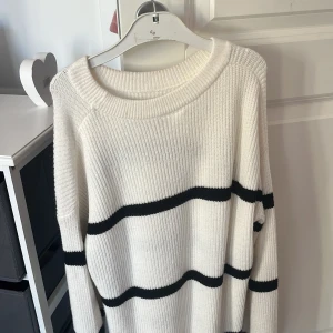 Vit stickad randig tröja Kappahl - Vit stickad tröja från Kappahl med svarta horisontella ränder. Tröjan har en rund halsringning, lång ärm och ribbade muddar. Oversized och mysig passform, perfekt för kyliga dagar. Jag har nog använt den 5 gånger, säljer den för jag inte längre vill ha den😊