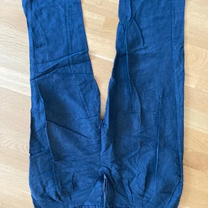 Mörkblå linnebyxor från Wera - Snygga mörkblå linnebyxor från Wera i rak modell. Byxorna har dragkedja och knapp framtill samt diskreta bakfickor. Perfekta för dig som gillar en stilren och avslappnad look.