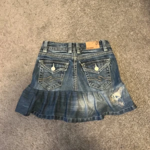 Jeanskjol med volanger  - Säljer en jeanskjol med volanger som är egenskydd från jeans. Midjemått 36 cm | Längd fram 33 cm | Längd bak 37 cm | Märket är Blue Monkey. Kan inte visa på då den är för liten för mig 💗