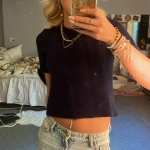 Mörkblå stickad topp  - Säljer en mörkblå croppad stickad tröja från Zara. Tröjan har korta ärmar, rund halsringning och ribbade kanter. Perfekt till jeans eller kjol för en chill och stilren look.