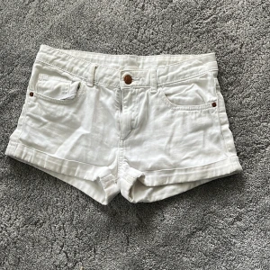 Vita jeansshorts från H&M💗 - Snygga vita jeansshorts från H&M med klassisk femficksdesign och uppvikta benslut. Shortsen har normal passform, bälteshällor och stängs med knapp och dragkedja. Perfekta för varma sommardagar och enkla att matcha med allt.💗