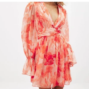 Blommig kortklänning med v-ringning och volang  - Säljer denna super populära klänningen, prislappen sitter kvar och klänningen är oanvänd för att den va lite stor. Perfekt plagg till sommaren och för fest!