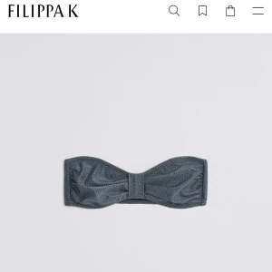 Mönstrad bandeau bikini från Filippa K - Snygg bandeau bikiniöverdel från Filippa K i blått med diskret prickigt mönster i grått. Toppen har en smickrande form med twistad front och metallspänne bak. Endast använd ett fåtal gånger. Nypris 900kr