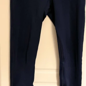 Mörkblå leggings från Reebok - Snygga mörkblå leggings från Reebok med klassisk logga baktill. De har en tight passform och är gjorda i ett stretchigt syntetmaterial som passar perfekt till träning eller chill. Midjan är hög och sömmarna är markerade för extra stil. Storleks lappen är bortklippt.