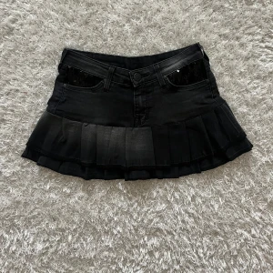 Svart  jeanskjol  - Lågmidjad jeanskjol omsydd från ett par jeans. Midjemått tvärsöver - ca 33  Längd - 29 cm