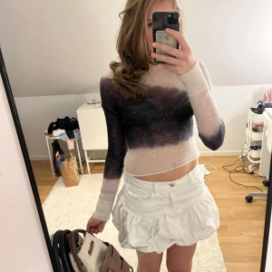 Weekday tröja - Säljer en stickad croppad tröja med lång ärm och coolt färgskiftande mönster i svart och beige. Tröjan är tunn och har en tight passform, perfekt att styla med kjol eller jeans. Supermjuk och trendig vibe!