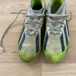 Adidas Crazyfast fotbollsskor gul/svart  - Säljer ett par Adidas Crazyfast fotbollsskor i grått, svart och neongult. Skorna har snörning, klassiska svarta ränder på sidorna och dobbar för bra grepp på planen. Ovandelen är i syntetmaterial och insidan har en bekväm fotbädd. Perfekta för dig som vill sticka ut på matchen.
