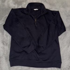Mörkblå half zip sweatshirt - Mörkblå sweatshirt med half zip och hög krage. Tröjan har långa ärmar och ribbade muddar vid ärmslut och nederkant. Perfekt för lager-på-lager och chill dagar. Materialet känns mjukt och skönt, troligtvis bomull eller bomullsblandning.