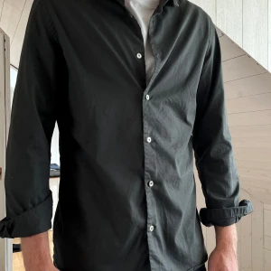 Grön skjorta från MNG - Snygg mörkgrön skjorta från MNG i slim fit-modell. Skjortan har långa ärmar, klassisk krage och vita knappar framtill. 