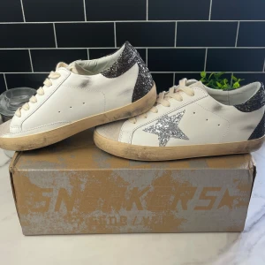 Golden goose skor - Snygga Golden Goose sneakers med glittriga silvriga detaljer. Skick 10/10 (som nya) och allt OG medföljer. Storlek 37, passar 37-38. Vanligt nypris ca 5500, sả först till kvarn e . Perfekta för dig som vill sticka ut med en cool och trendig look.