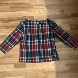  topp från GANT  - Säljer en snygg rutig topp från GANT i bomull. Färgerna är marinblå, röd, beige och vit. Toppen har trekvartsärm och dragkedja i nacken. Perfekt för dig som gillar klassisk och preppy stil.