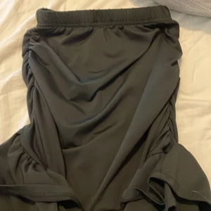 Svart volangkjol från SHEIN Teen - Supersnygg svart kjol från SHEIN Teen med volangkant och rynkade detaljer på sidorna. Kjolen har resår i midjan för skön passform och är perfekt för dig som gillar en trendig och enkel stil. Materialet känns lätt och flowy.