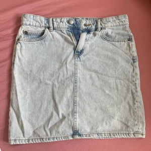 Ljusblå jeanskjol från Lindex - Säljer en ljusblå jeanskjol från Lindex i klassisk femficksmodell. Kjolen är kort, har bälteshällor och dragkedja framtill. Perfekt för dig som gillar en enkel och tidlös denimlook. Passar till allt och är superenkel att styla. Använd 2 gånger 