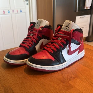 Nike Air Jordan 1 High röd/svart/vit - Säljer ett par Nike Air Jordan 1 High i klassisk röd, svart och vit färg. Skorna har snörning, rund tå och är tillverkade i skinn. Perfekta för dig som vill sticka ut med en ikonisk sneaker med cool retrostil. Är i bra skick och använda ett fåtal gånger. Priset kan ändras vid snabbt köp! Kontakta vid fler frågor eller bilder.