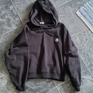 Svart hoodie från Moncler, XL - Svart hoodie från Moncler i oversized modell med huva och snörning. Tröjan har ett broderat Moncler-märke på bröstet och är tillverkad i mjuk bomull. Långärmad och perfekt för höst och vinter. Snygg och enkel att matcha till det mesta.