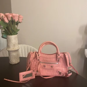 Balenciaga väska - Säljer en superfin rosa balenciaga handväska. Perfekt för dig som vill sticka ut med en färgglad accessoar. Väskan är knappt använd och ser helt ny ut.