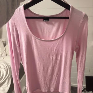 Ljusrosa långärmad topp Gina Tricot - Säljer en ljusrosa långärmad topp från Gina Tricot med rund, djup ringning. Tunn och mjuk i materialet, perfekt för lager-på-lager eller som den är. Enkel och stilren design som passar till många olika outfits.