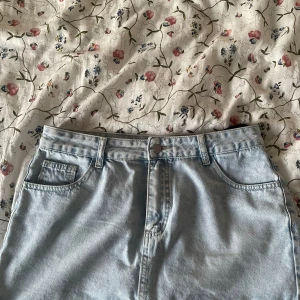 Ljusblå jeanskjol  - Säljer en ljusblå stretchig jeanskjol. Kjolen har raka linjer och bakfickor, perfekt för en avslappnad och trendig stil. Färgen är ljusblå denim.