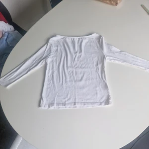 Vit off shoulder tröja från lager 157 - En basic vit långärmad tröja från 157 i mjuk bomullsblandning med lite stretch. Enkel och clean design med rund halsringning, perfekt att styla med jeans eller kjol. Materialet är 94% bomull och 6% elastan för en skön passform.