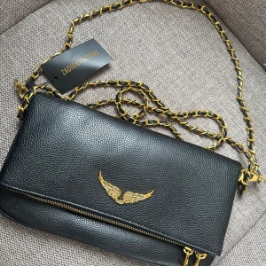 Svart axelväska Zadig & Voltaire - Svart axelväska i skinn från Zadig & Voltaire med guldfärgad kedjerem. Väskan har dragkedja och detaljer i guld🩷 använd få gånger🩷 kan gå ner i pris vid snabb affär🩷fick väskan i present🩷