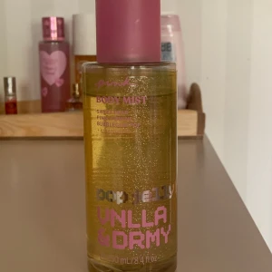 PINK Pop Jelly Vanilla & Dreamy Body Mist - Body mist med doft av söt päron, rosa jasmin och bubbelgum. Flaskan är transparent med guldigt glitter och rosa text, rymmer 250 ml. Innehåller eteriska oljor och är vegansk, utan konstgjorda färgämnen. Perfekt för dig som gillar söta, fruktiga och nostalgiska Y2K-dofter.