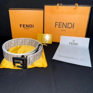 Vitt Fendi bälte med FF-logga - Snyggt beige bälte från Fendi med ikoniskt FF-mönster runt om och stor svart metallspänne. Bältet har en modern och lyxig vibe, perfekt för att lyfta vilken outfit som helst. Kommer med originalförpackning och certifikat. Kom med prisförslag!!!!