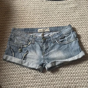 Vintage lågmidjade jeansshorts🔥🔥🔥 - Snygga ljusblå jeansshorts från Gallop med uppvikta ben och coola fickdetaljer med tvinnade sömmar. Klassisk femficksmodell, låg midja och knappgylf. midjemått 41 cm😁 Tryck ej köp nu