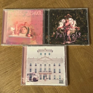 After School EP, Portals, K-12 - Tre unika CD-album av Melanie Martinez: 'After School EP', 'Portals' och 'K-12'. Perfekt för dig som gillar kreativ pop, starka visuella koncept och originella berättelser. Omslagen är färgstarka och fantasifulla – en samling som sticker ut i hyllan och passar unga vuxna med känsla för stil. Köpta på bengans. 1st- 59kr, 2st- 89kr, 3st- 119kr