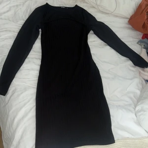 Svart ribbad långärmad klänning - Snygg svart ribbad klänning med lång ärm och kroppsnära passform.  Klänningen har rund halsringning och är i ett stretchigt material.