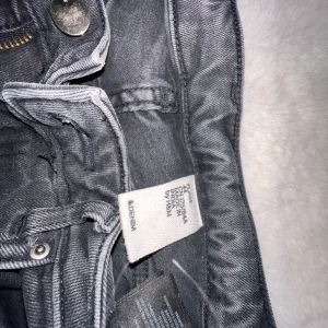 Svarta raka jeans från Adenina - Snygga svarta jeans från Adenina med utsvängda ben och råa kanter nertill. Klassisk femficksmodell med dragkedja och knapp framtill. Jeansen har en mörk tvätt och är tillverkade i ett slitstarkt denimtyg. Storlek 42 men sytt om själv så de passar 38