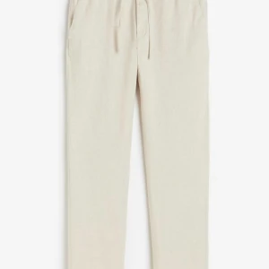 Beiga linnebyxor med snörning - Snygga och luftiga beiga linnebyxor med avslappnad passform och snörning i midjan. Perfekta för varma dagar och ger en chill vibe till din outfit. Byxorna har raka ben och sidfickor. Helt sprillans nya