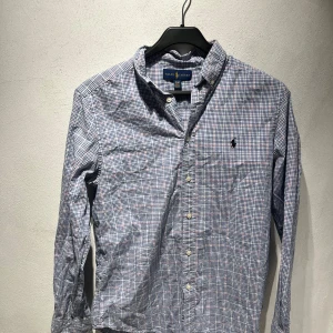 Rutig skjorta från Ralph Lauren XL - Klassisk rutig skjorta från Ralph Lauren i storlek XL. Skjortan har blå, röda och vita rutor, knappar framtill och lång ärm.  Väldigt bra skick.