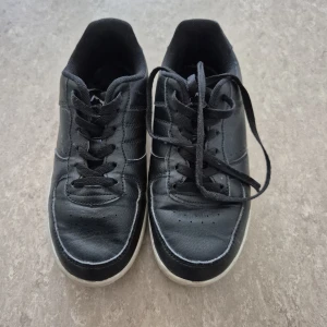 Sneakers - Säljer ett par svarta sneakers från NoNation i storlek 38. Skorna har en klassisk design med snörning och en vit sula. Dom är väl använda. (Men inget hål). Perfekta för en avslappnad stil.