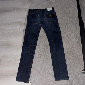 Stone Island mörkblå jeans straight fit - Mörkblå jeans från Stone Island med klassisk femficksdesign och ikonisk logotyp på bakfickan. Jeansen har raka ben och snygga kontrastsömmar. Tillverkade i slitstarkt denim med en stilren look som passar till det mesta. Jeansen är i bra skick. Storlek W29, L34.   Pris kan diskuteras!