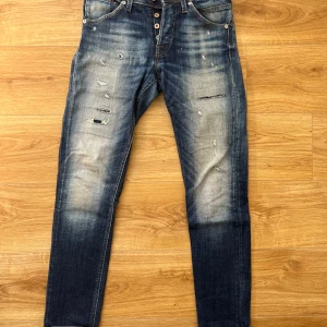Jeans från Jack&Jones - Mörkblåa jeans med sliten design på framsida lår. Tre fickor fram och två bak. Knappar istället för gylf. Storlek se bild. Slimfit. Material: 98% bomull och 2% elastan. Från Jack&Jones. Sparsamt använda, så de är i gott skick!