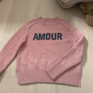 Rosa stickad tröja Zadig & Voltaire - Säljer en rosa stickad tröja från Zadig & Voltaire med mörkblå text 'AMOUR' framtill💘 Är i barnstorlek och skulle säga att det passar xs-s 