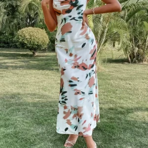 Vit långklänning med blommigt mönster - Säljer en vit långklänning med blommigt mönster i rosa, grönt och svart. Klänningen har smala axelband som korsas i ryggen och en öppen rygg med snörning. Materialet är glansigt och känns lyxigt, perfekt för varma dagar. Snygg passform och flowy känsla.