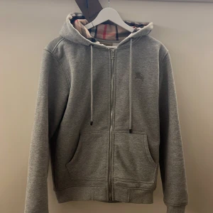 Grå zip hoodie från Burberry  - Säljer nu min grå zip hoodie från burberry, mycket fint skick och hoodien är aldrig använd endast testad. Storleken är S och passar dig som är 170-182 ungefär skulle jag säga 